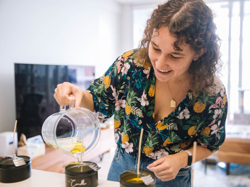 A woman pouring melted wax at a candle making class.